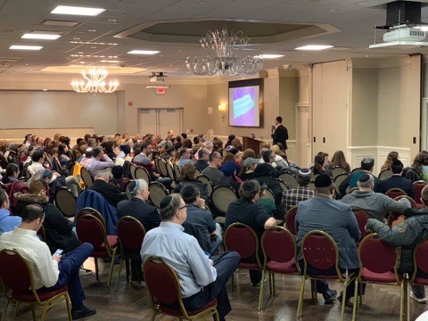 Rabbi Moshe Zeldman speaking to a packed audience
